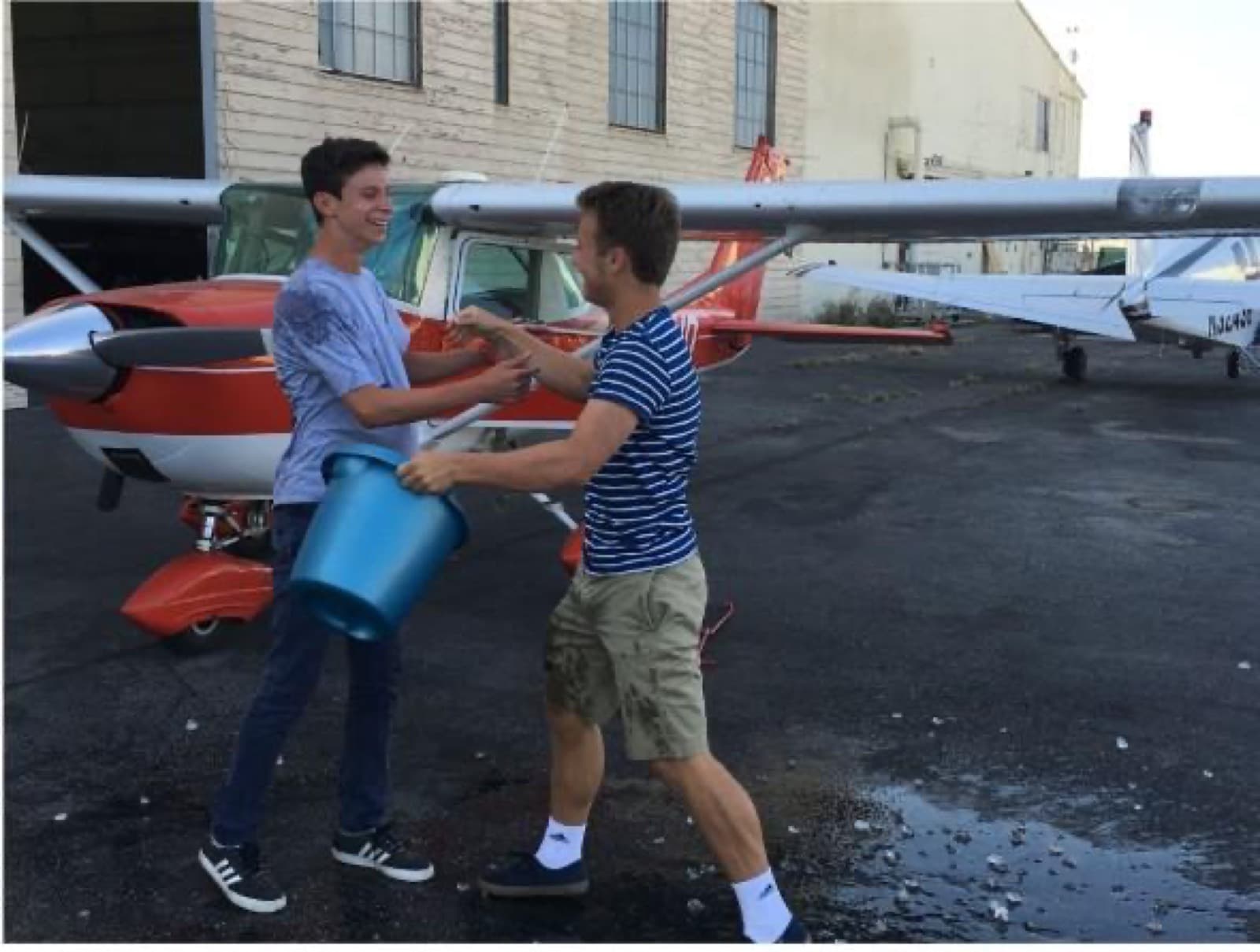 High school student beside a small airplane during hands-on aviation training